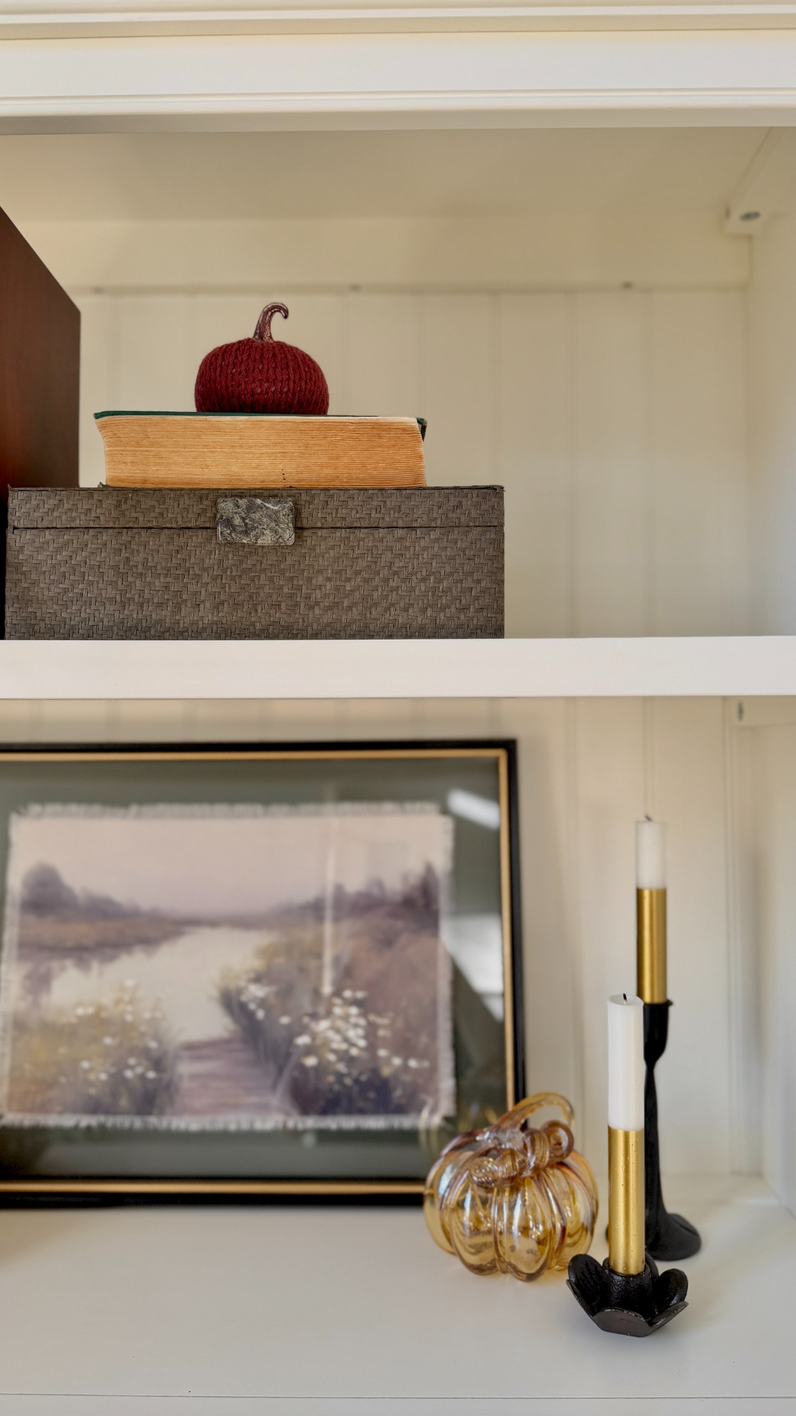 Small burgundy pumpkin resting on stacked books and box.